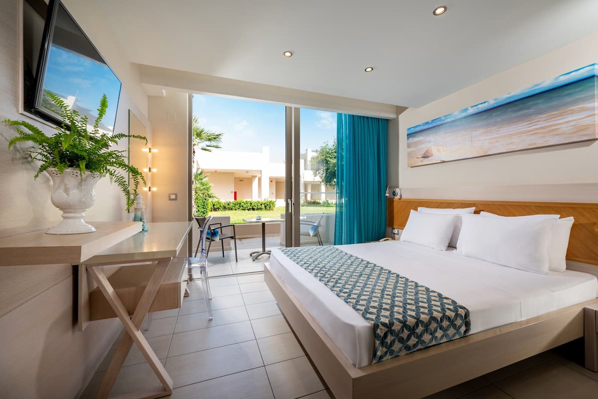 Habitación de hotel moderna con una cama grande, un escritorio, una planta en maceta y vistas al exterior.