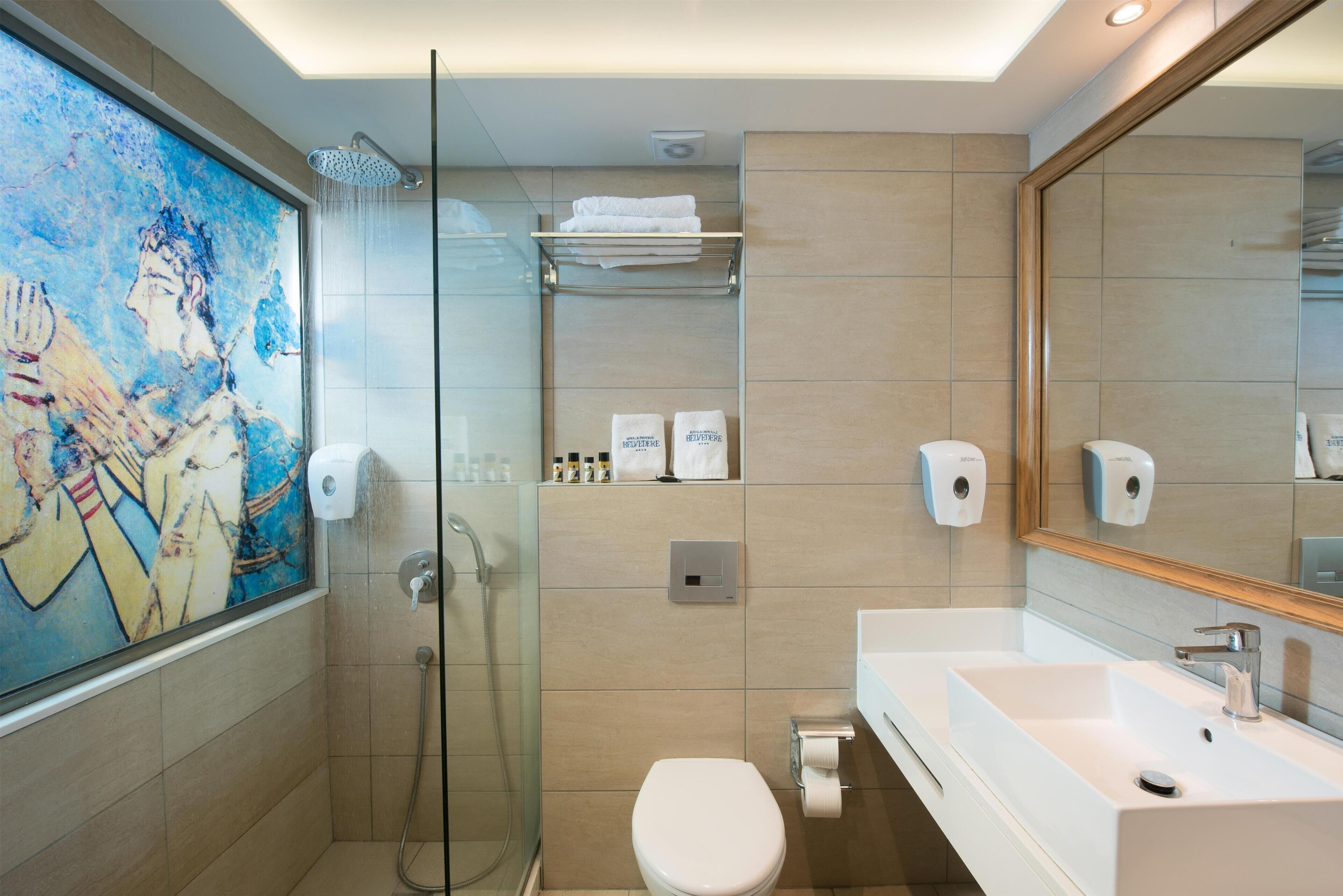 A modern bathroom with a glass shower enclosure, a toilet, a sink with a mirror, and a towel rack.