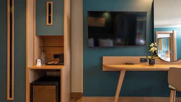 Une chambre moderne avec un bureau en bois, un miroir et un téléviseur fixé au mur.