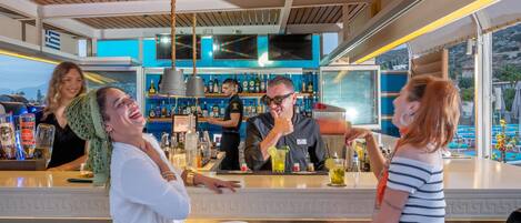 A bar area with a counter, bar stools, and a bartender.