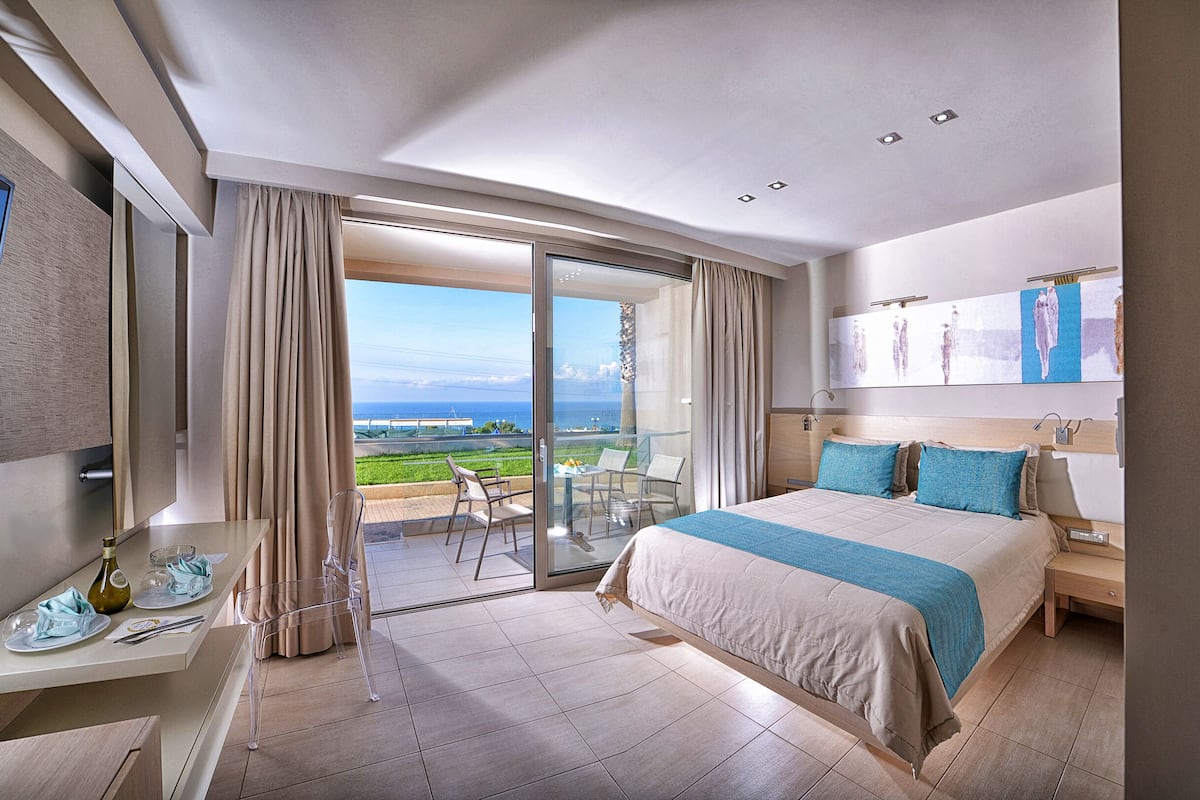 Una habitación de hotel moderna con una cama grande, un escritorio y un balcón con vistas.