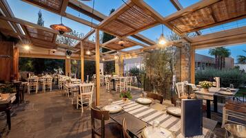 Un espace extérieur aménagé pour les repas, avec des tables et des chaises, une pergola et une vue sur le paysage environnant.