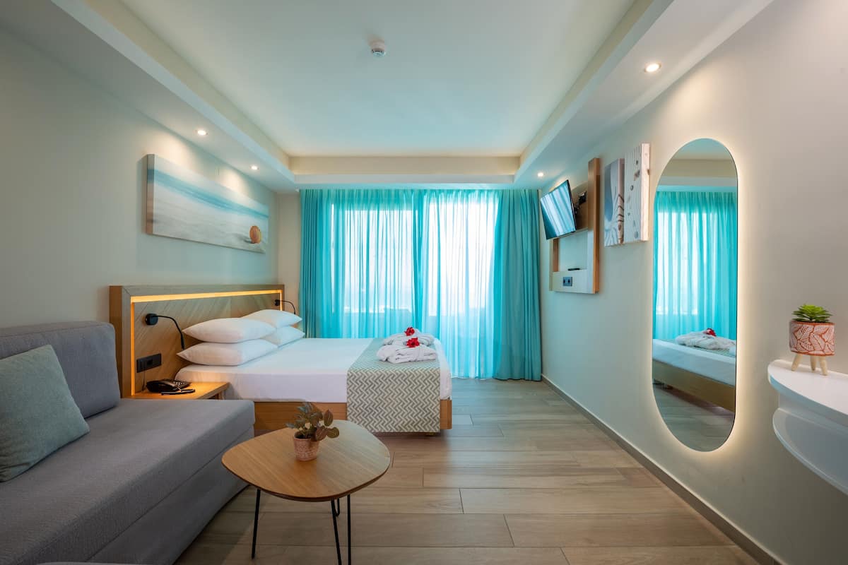 Una habitación de hotel moderna con cama, sofá y una mesita con una planta.