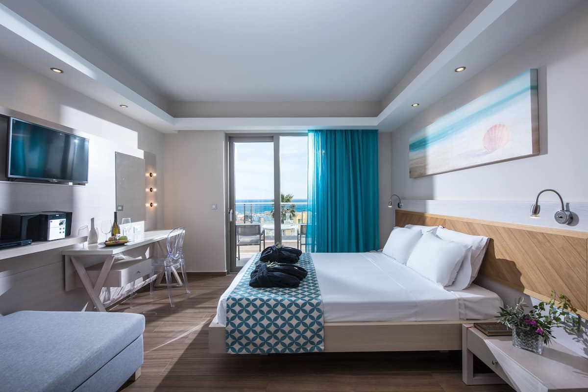 Habitación de hotel moderna con cama, escritorio, televisión y vista al mar.