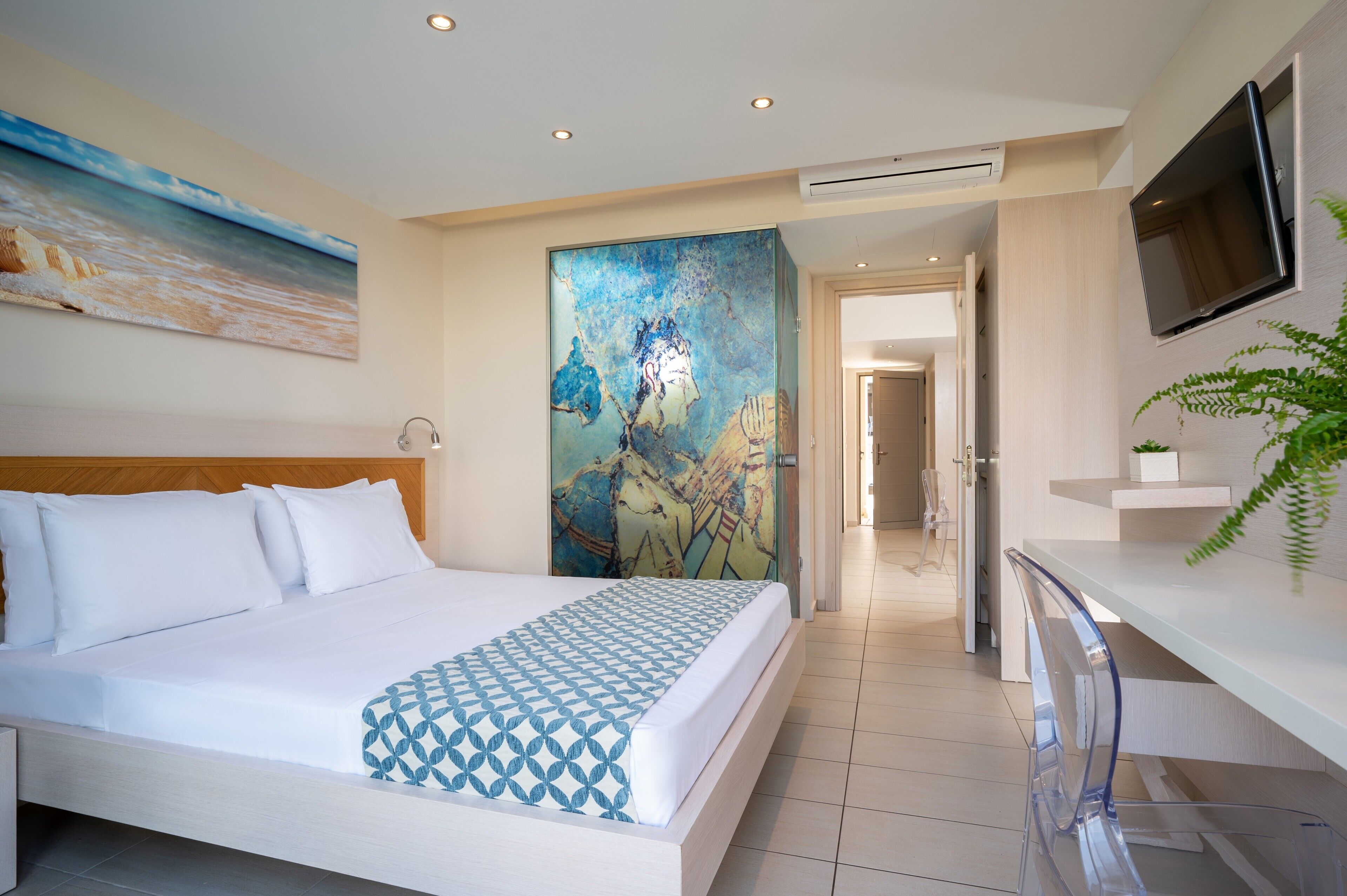 Una habitación de hotel moderna con una cama grande, un cuadro, un televisor y una planta.