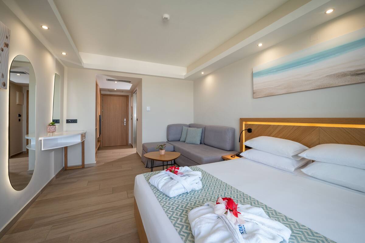Una habitación de hotel moderna con una cama, un sofá, una mesita y un espejo.