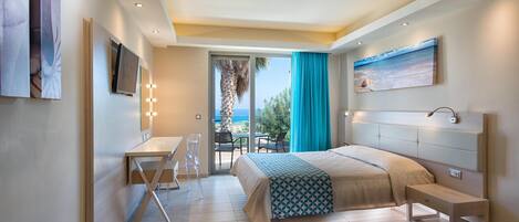 A modern hotel room with a bed, bedside table, and a desk with a chair. There is a balcony with a view of the sea.