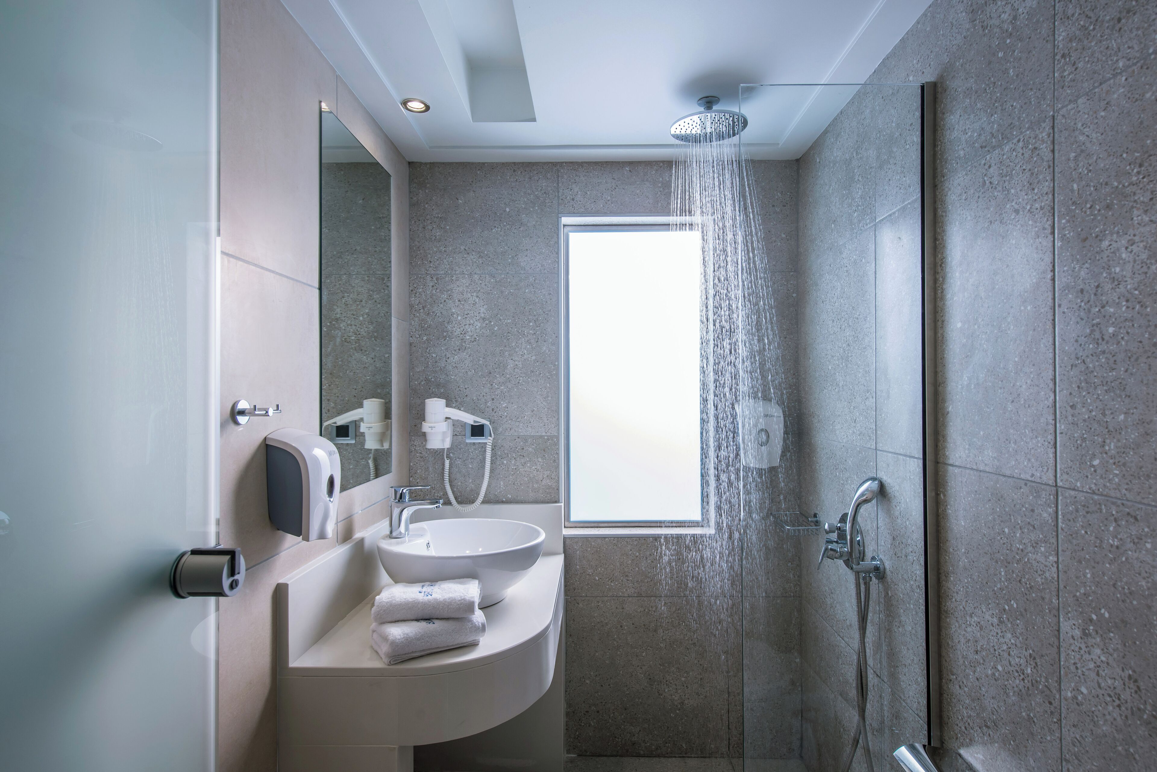 Un baño moderno con ducha, lavabo y espejo.