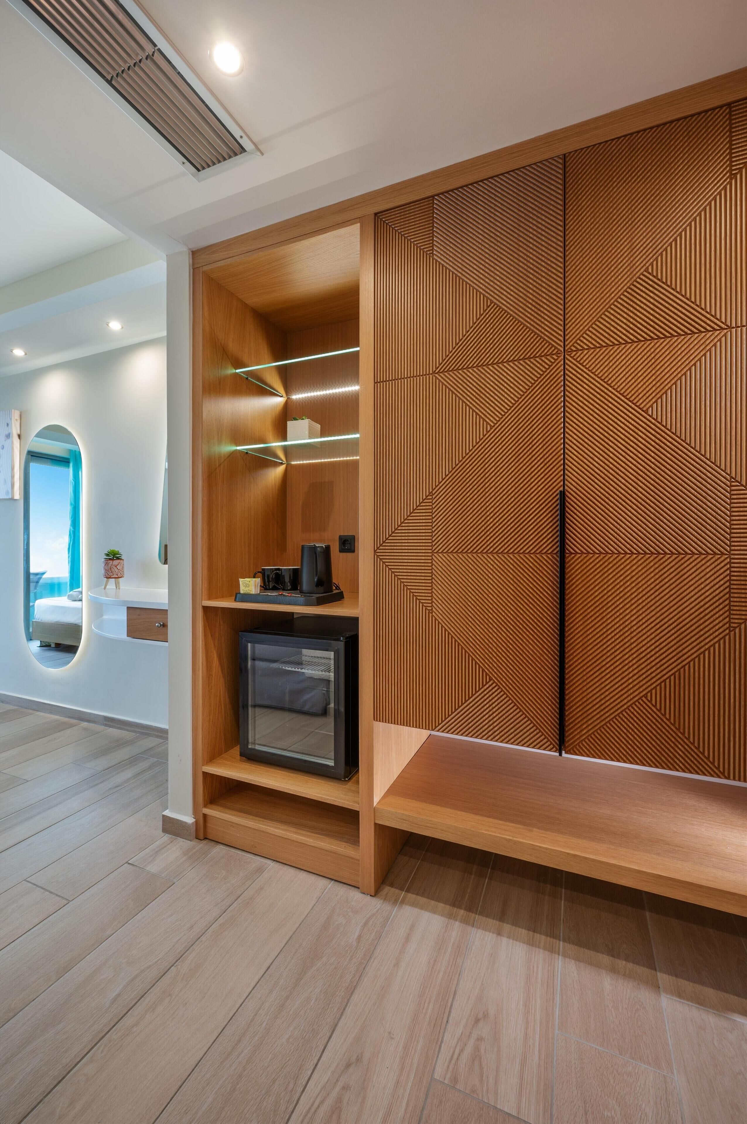 Ein modernes Hotelzimmer mit einem Holzschrank, einem kleinen Fernseher und einer fest installierten Ablagefläche.