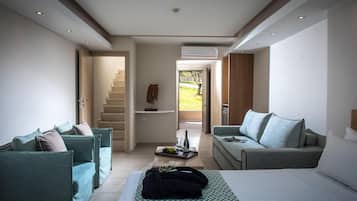 A modern hotel room with a bed, two sofas, a coffee table, and a staircase leading to a balcony.