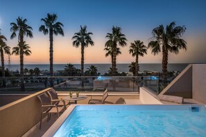 A rooftop pool area with a view of the ocean and palm trees.