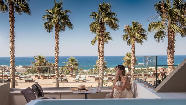 A balcony with a pool, palm trees, and a view of the beach and ocean. - Royal & Imperial Belvedere Resort - All inclusive (Hersonissos)
