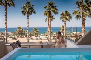 Un balcón con piscina, palmeras y vistas a la playa y al océano.