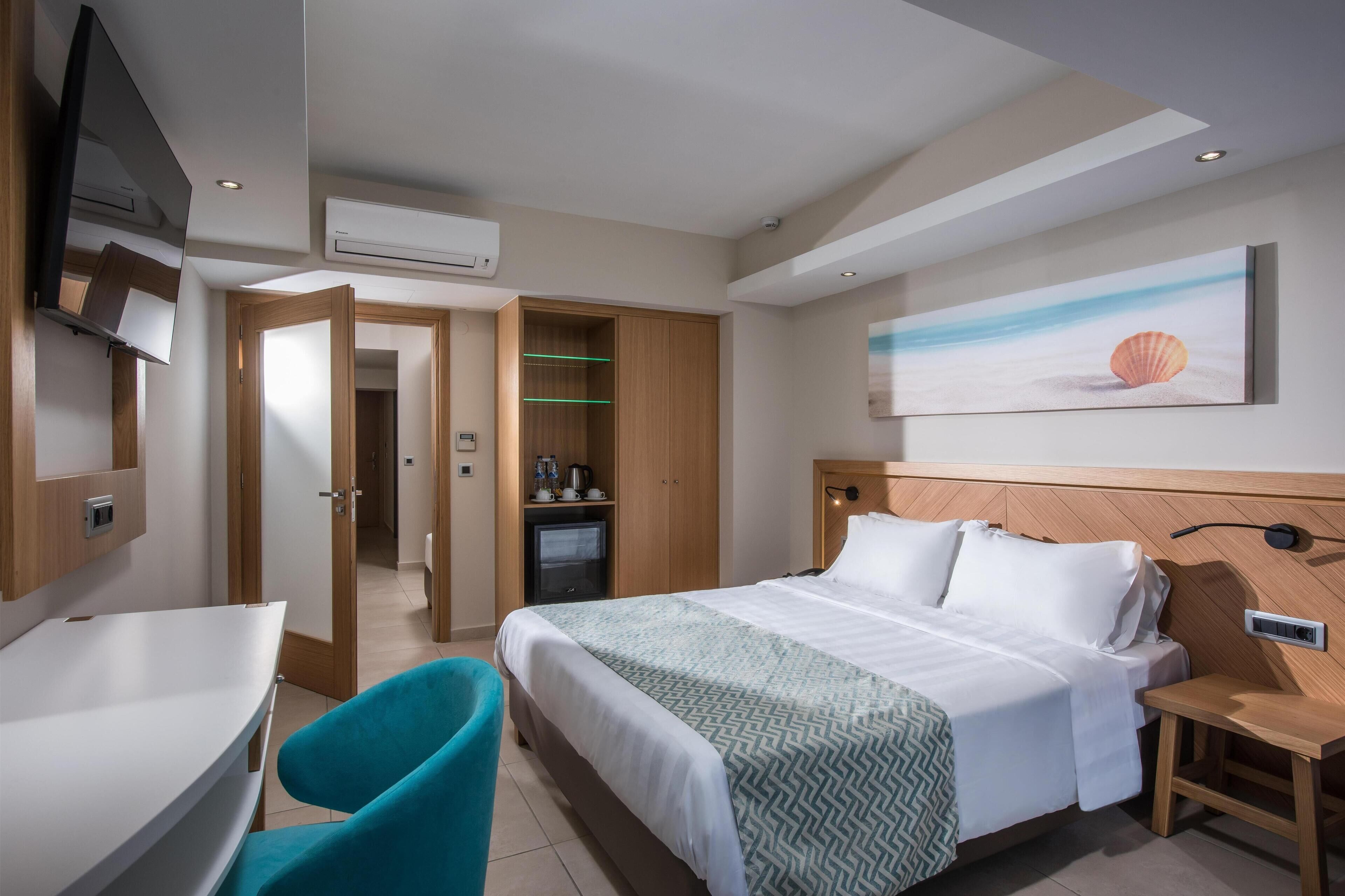 A hotel room with a bed, a desk, a chair, a TV, and a painting of a shell on the wall.