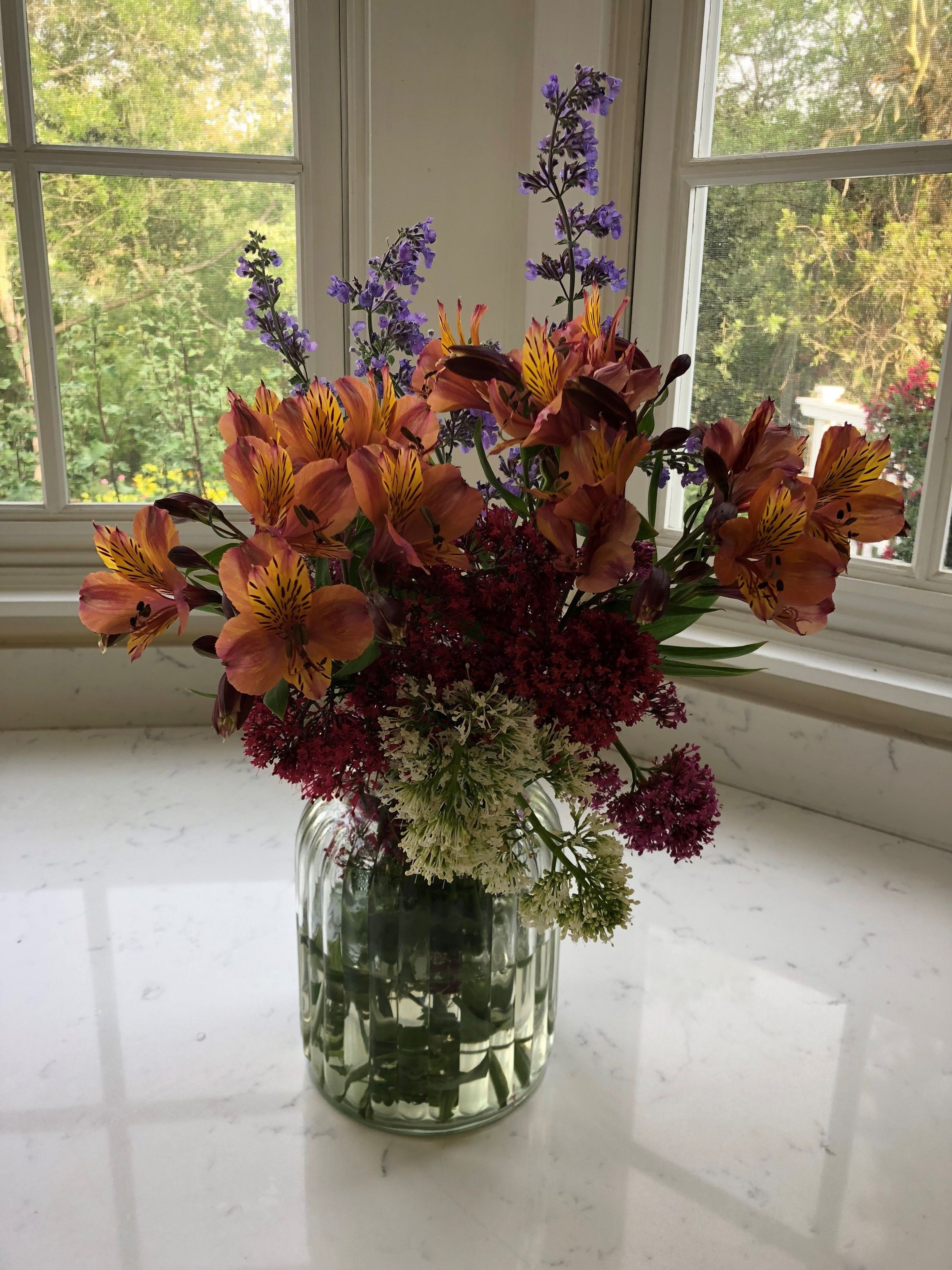 A clear view of a window with a vase of flowers on a marble surface.