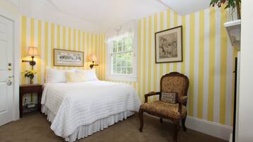 A bedroom with a bed, two bedside lamps, a chair, a window, and a door.