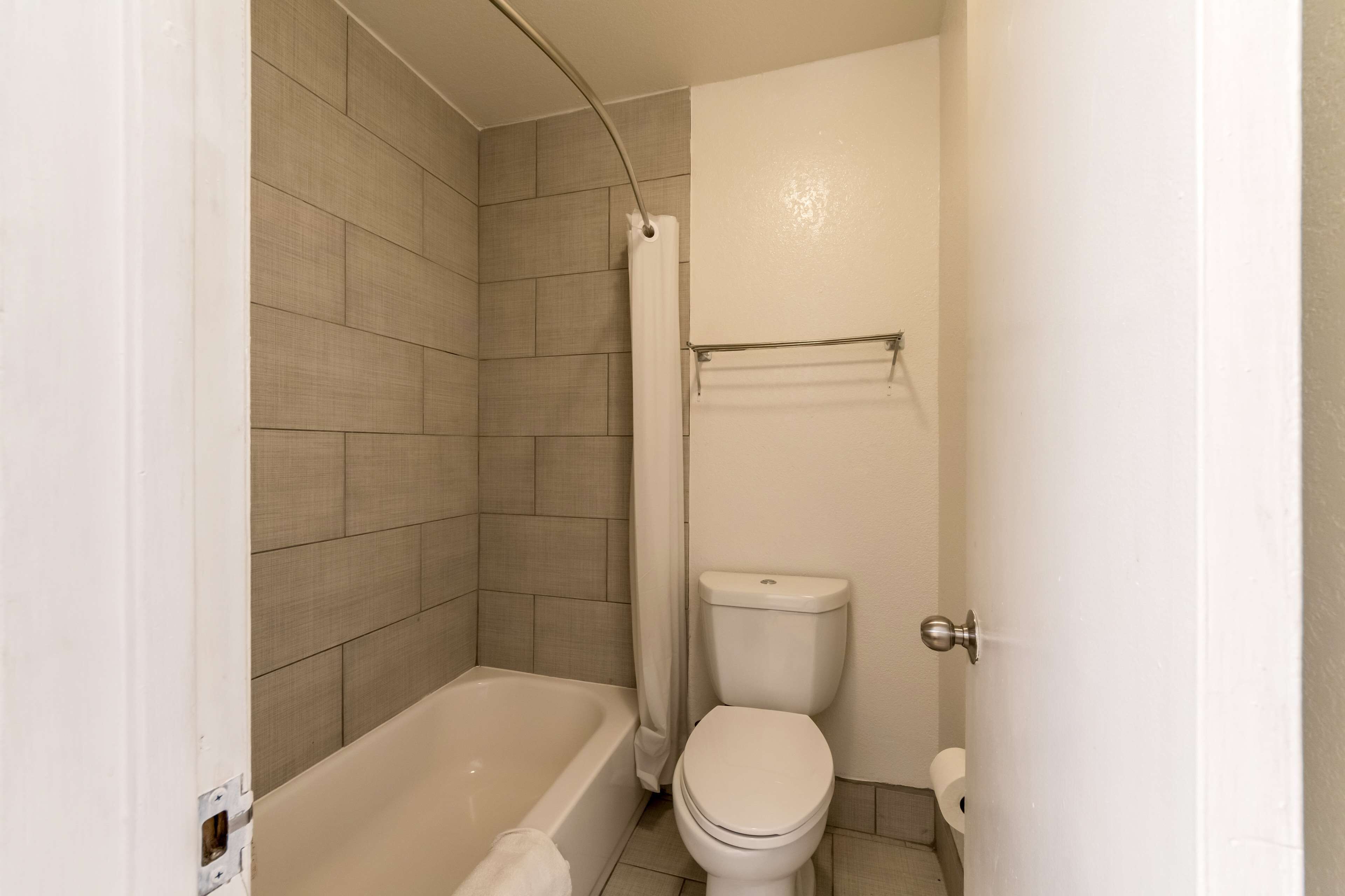 A bathroom with a bathtub, toilet, and shower curtain.
