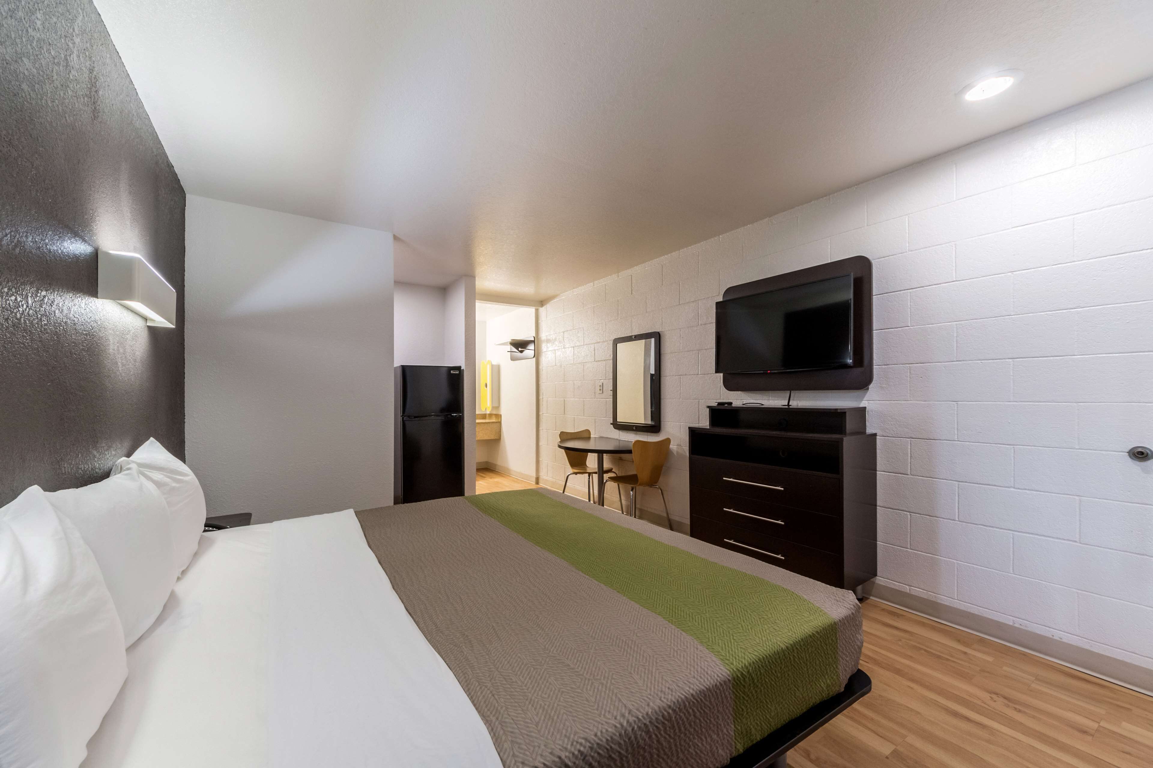 Una habitación de hotel con cama, televisión, escritorio y silla.
