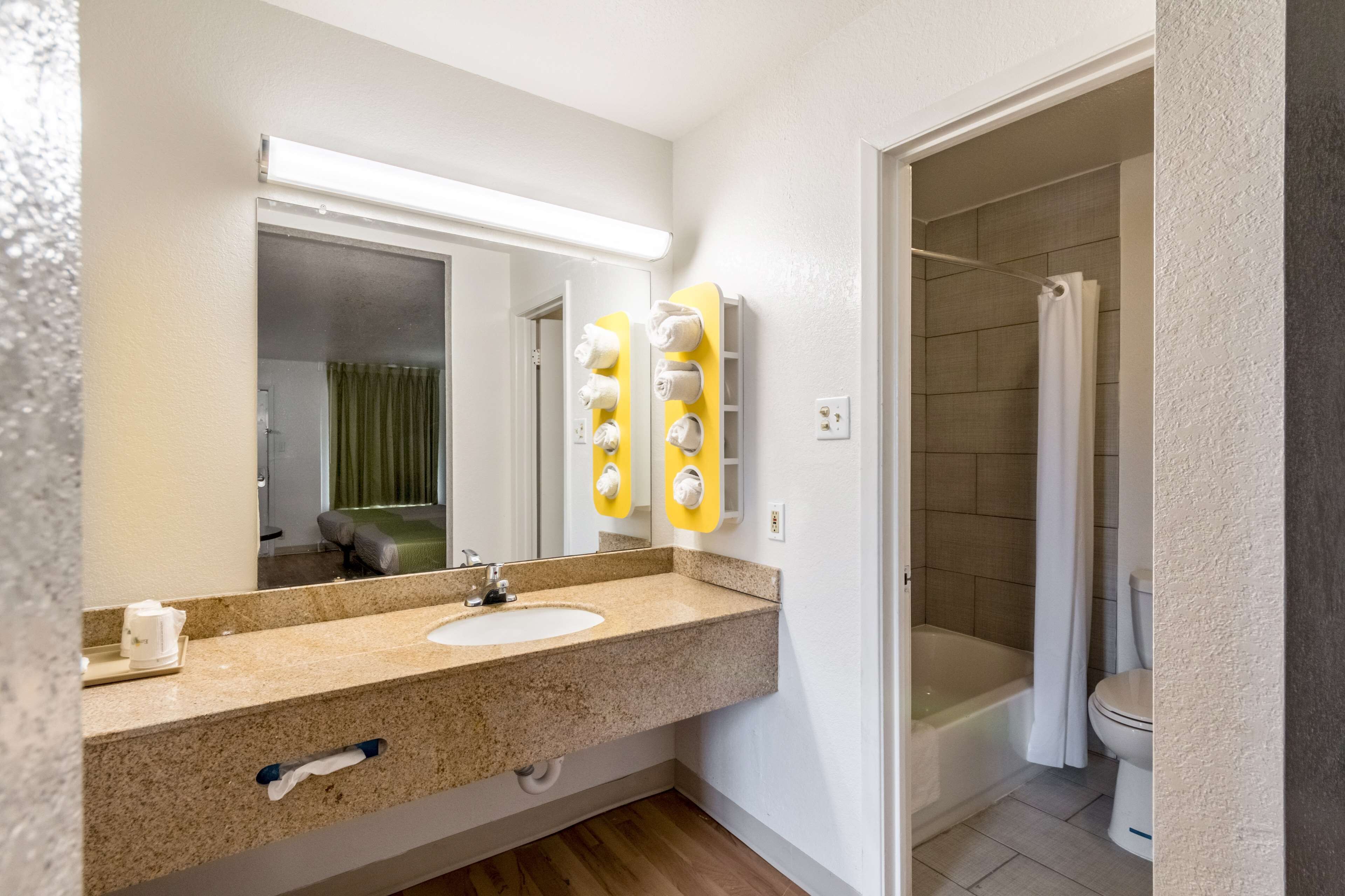 Ein Badezimmer mit Waschbecken, Spiegel, Handtuchhalter und Duschbereich.