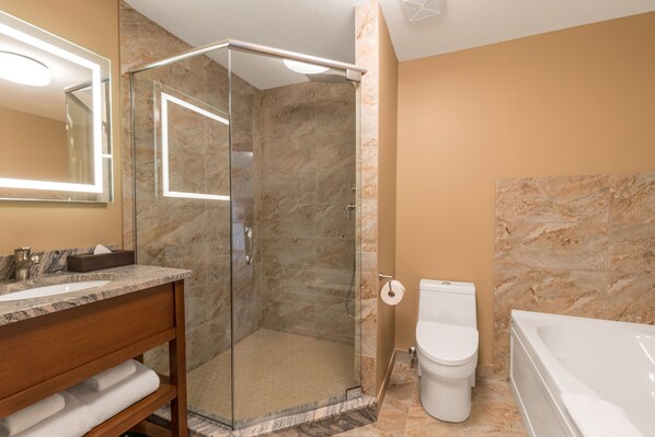 Un baño moderno con ducha acristalada, pared con azulejos de mármol, inodoro blanco y bañera.