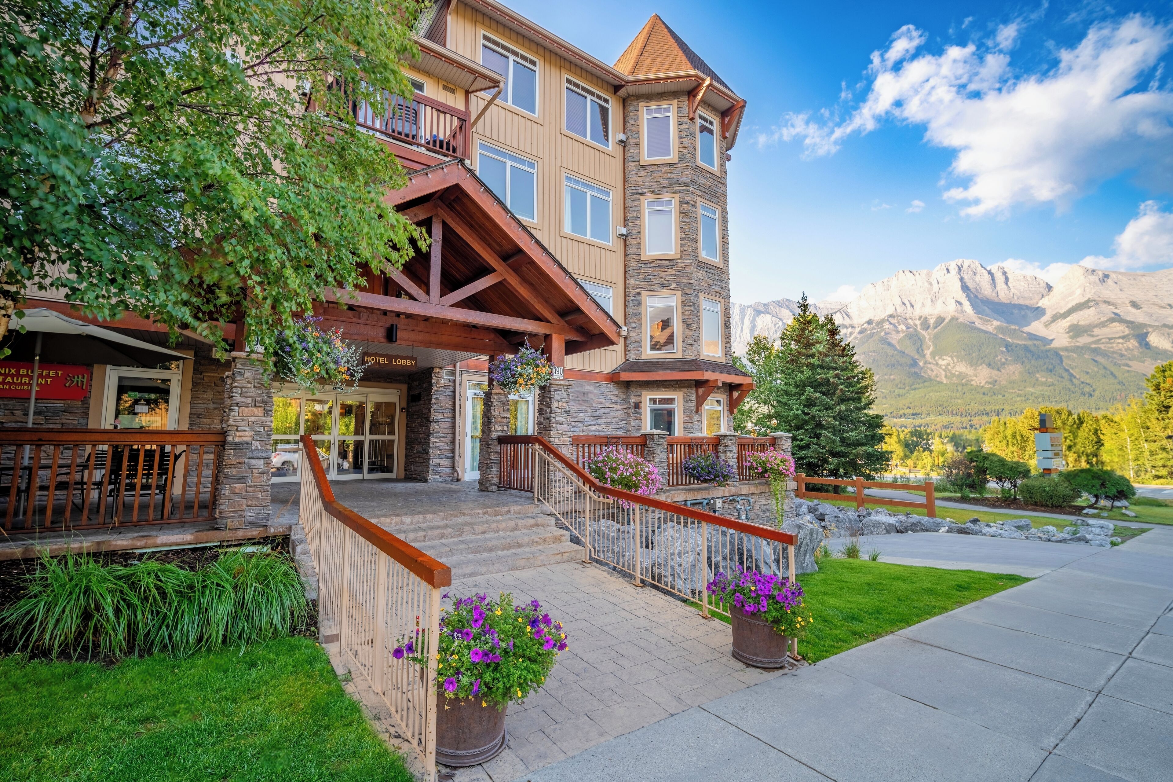 Ein mehrstöckiges Hotel mit einer Stein-Fassade, hölzernen Balkonen und Blick auf die Berge.
