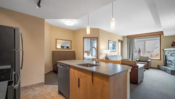 A modern kitchen with a built-in island, a dishwasher, and a refrigerator. There is a seating area with a sofa and chairs, and a fireplace.