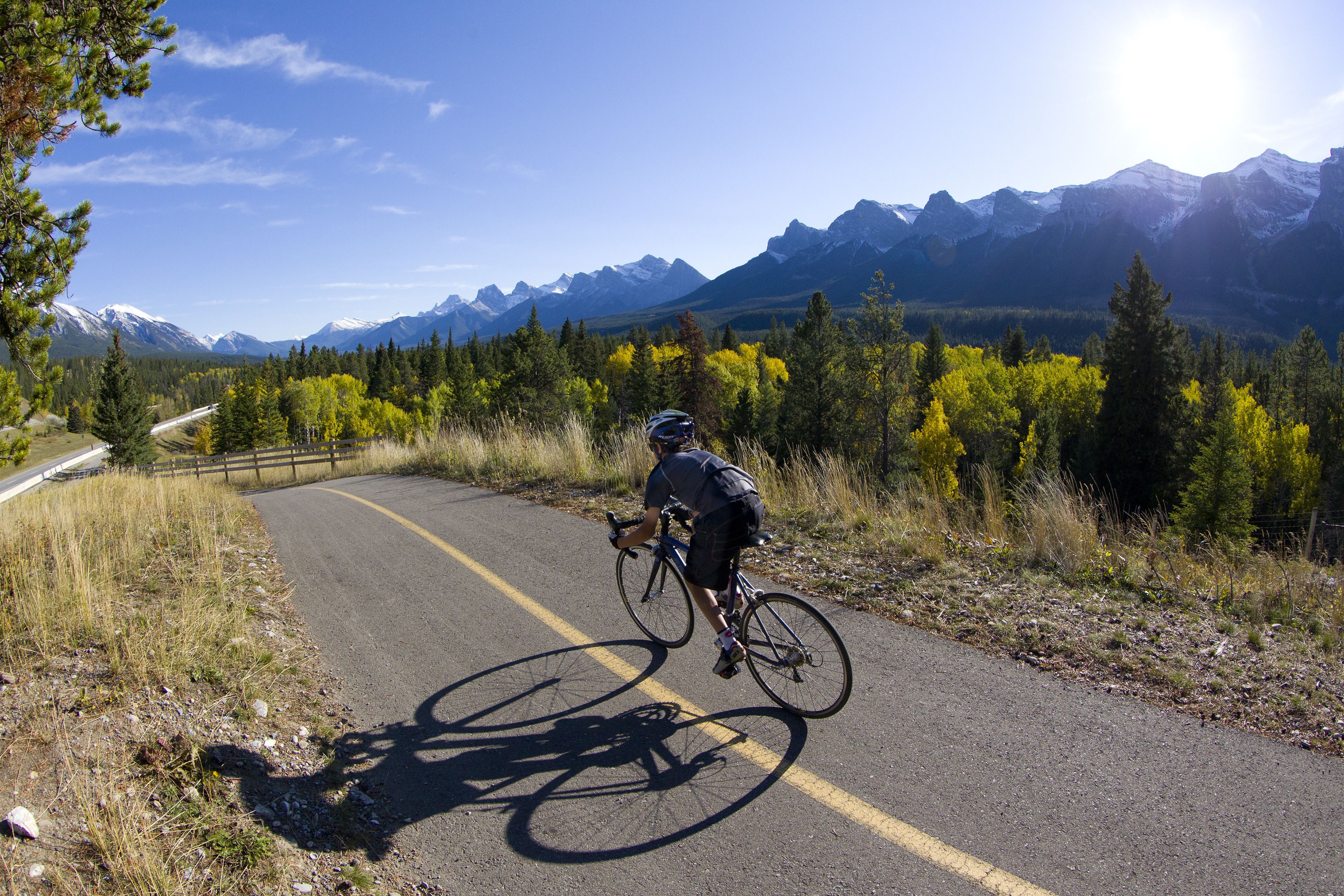 A cyclist on a paved road with mountains in the background.