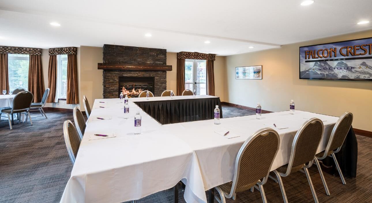 A conference room with a long table, chairs, a fireplace, and a mountain view.