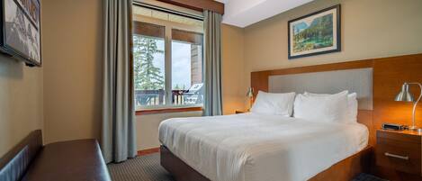 Una habitación de hotel con una cama grande, un banco, una mesita de noche y una ventana con cortinas.