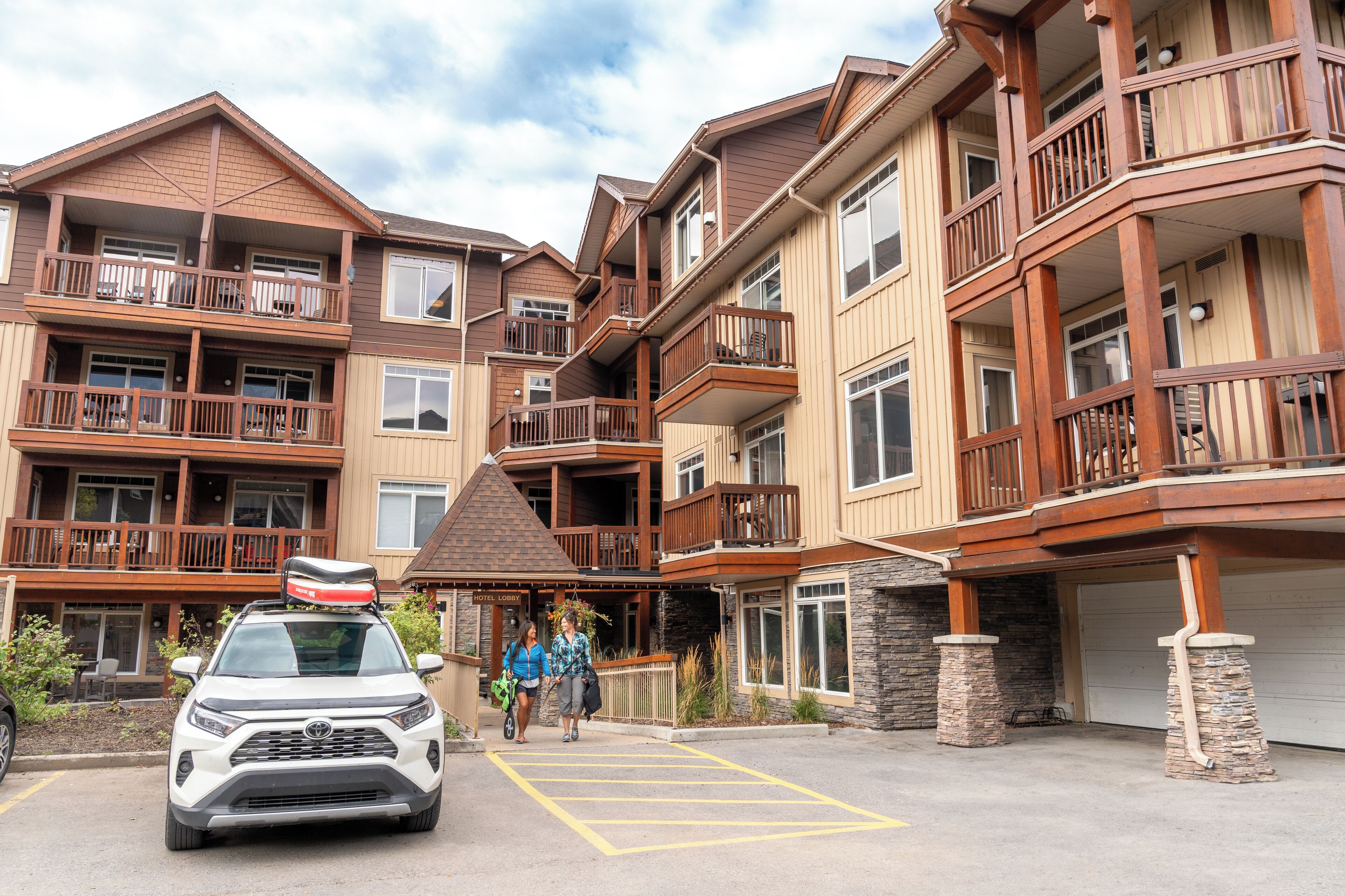 A multi-story hotel with balconies, a covered entrance, and a parking area.