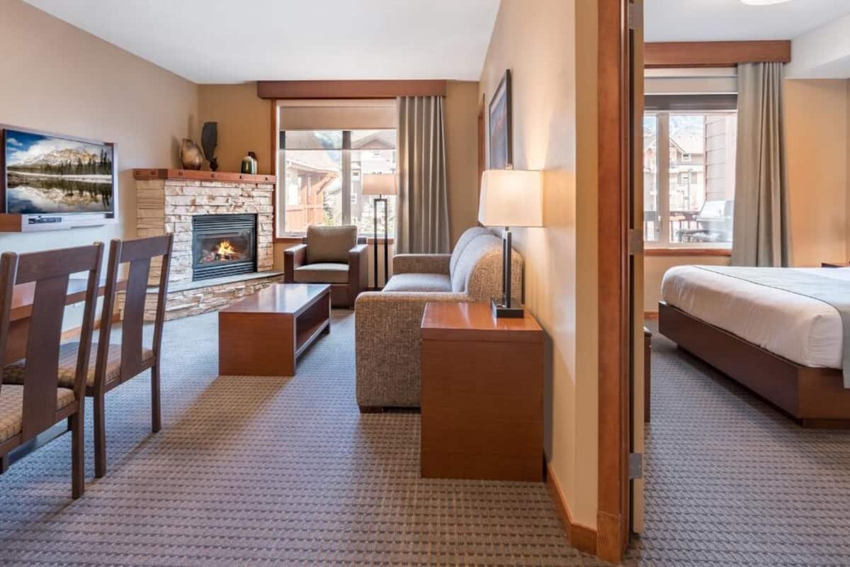Habitación de hotel con chimenea, sofá, cama, televisión y comedor.
