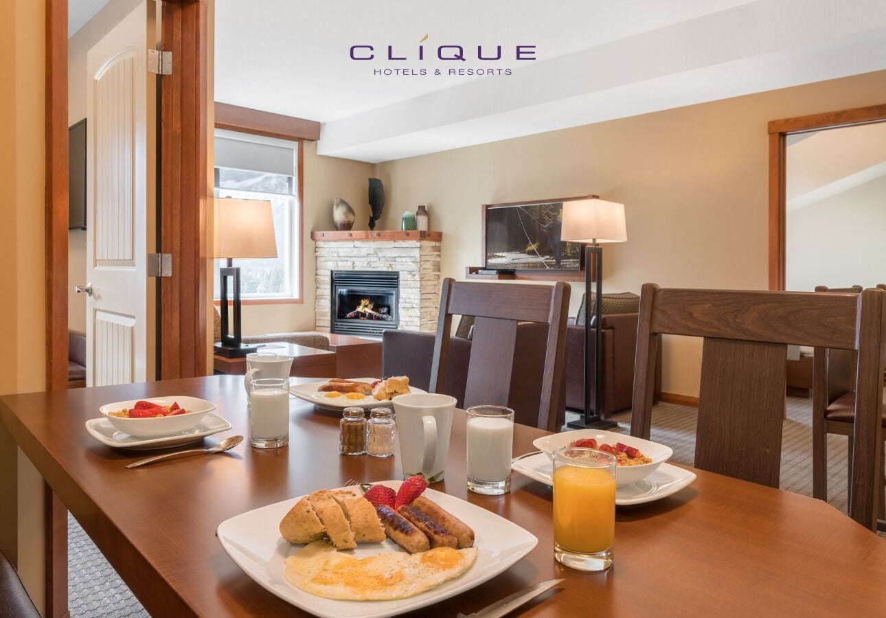 A dining area with breakfast plates, including eggs, sausages, and fruit, and a glass of orange juice.
