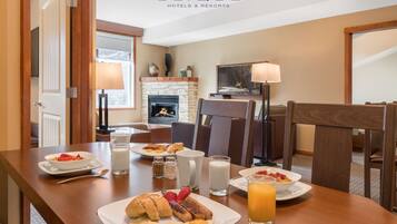 A dining area with breakfast plates, including eggs, sausages, and fruit, and a glass of orange juice.
