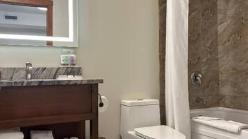 A bathroom with a marble sink, a toilet, a bathtub, and a shower curtain.