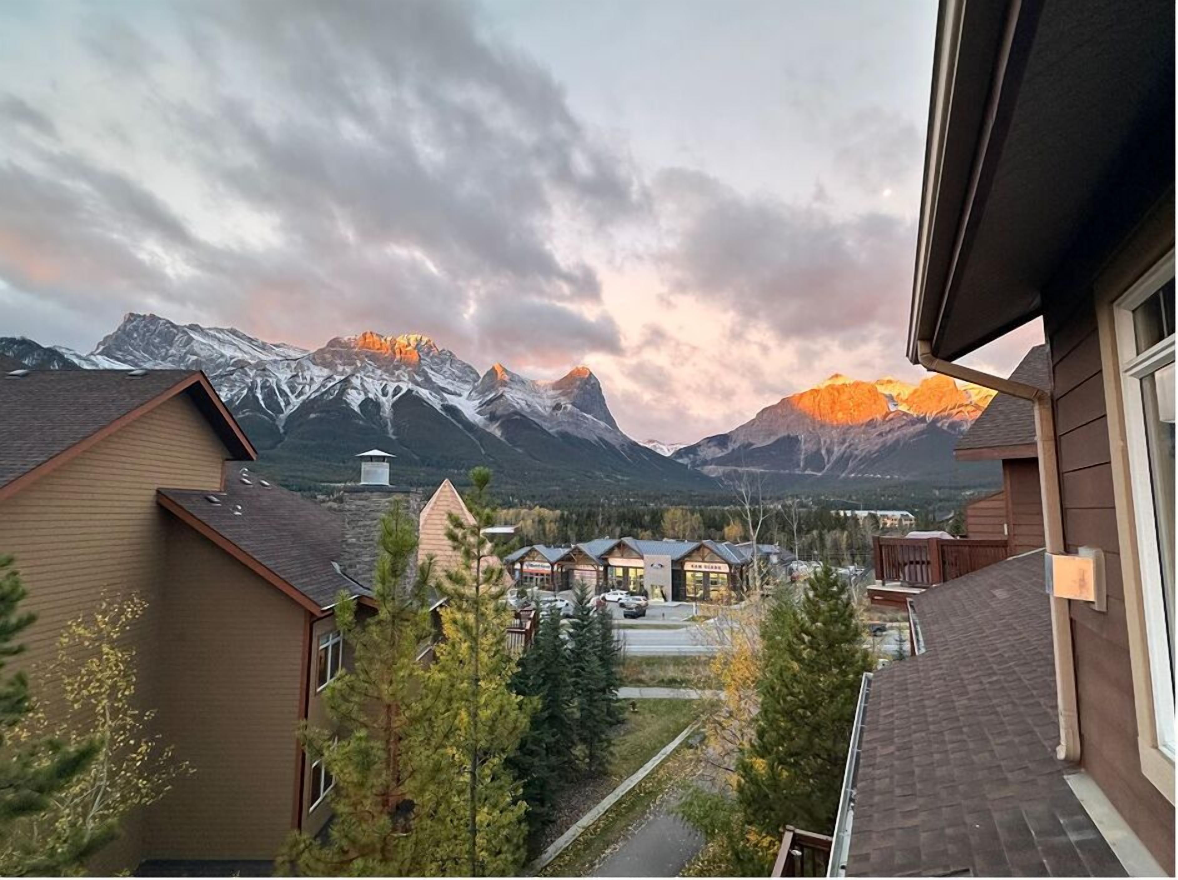 A residential area with houses, a small building, and a mountain range in the background.