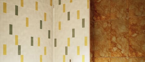 A modern bathroom with a shower, toilet, and marble wall.