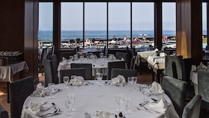Un restaurante con mesas dispuestas para comer, con amplias ventanas que ofrecen vistas a la playa.