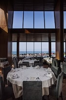 Un restaurante con mesas dispuestas para comer, con amplias ventanas que ofrecen vistas a la playa.