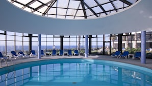 Una amplia piscina interior con vistas despejadas al océano a través de amplios ventanales.