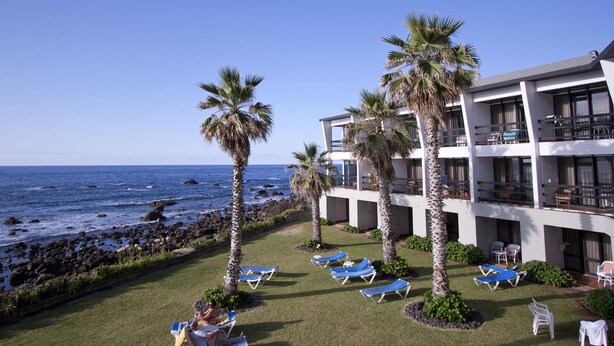 Un resort con piscina, palmeras y vista al océano.