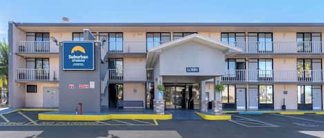 A Suburban Studios hotel with a modern design, a lobby entrance, and a parking area marked with 'No Parking' signs.