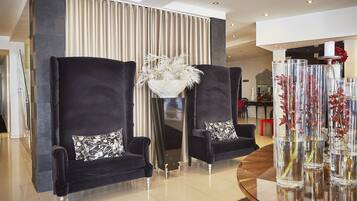 A modern living room with two black armchairs, a glass coffee table, and a decorative vase with white flowers.