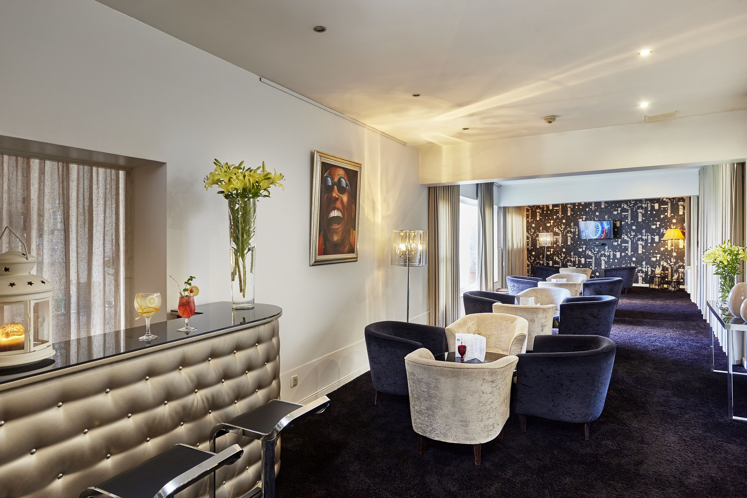 A modern lounge area with a bar, seating, and a cityscape view.