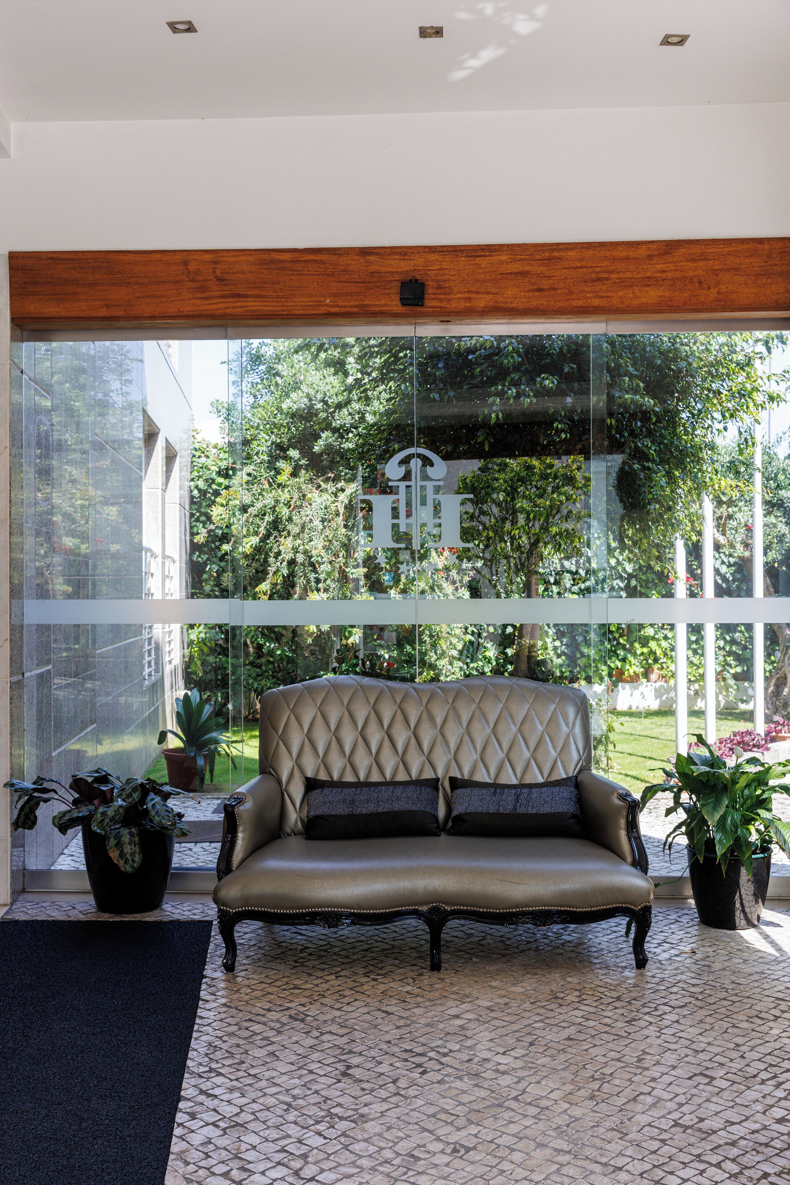 Un interior moderno con un sofá de cuero, ventanas amplias y plantas en macetas.