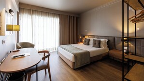 Una habitación de hotel moderna con cama, mesitas de noche, escritorio y una silla.