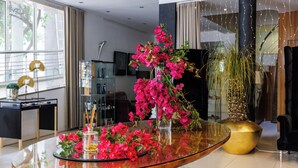 Un salón moderno con una mesa de centro de cristal, un jarrón dorado grande y una planta en maceta.