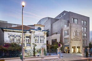 A hotel with a classic facade, a modern building next to it, and a cobblestone street. - Hotel As Américas (Aveiro)