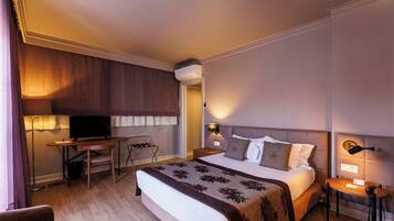 Una habitación de hotel con cama, escritorio, televisor, lámpara y teléfono.