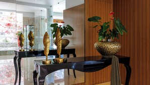 Un comedor moderno con una mesa de vidrio, sillas negras y detalles dorados decorativos.
