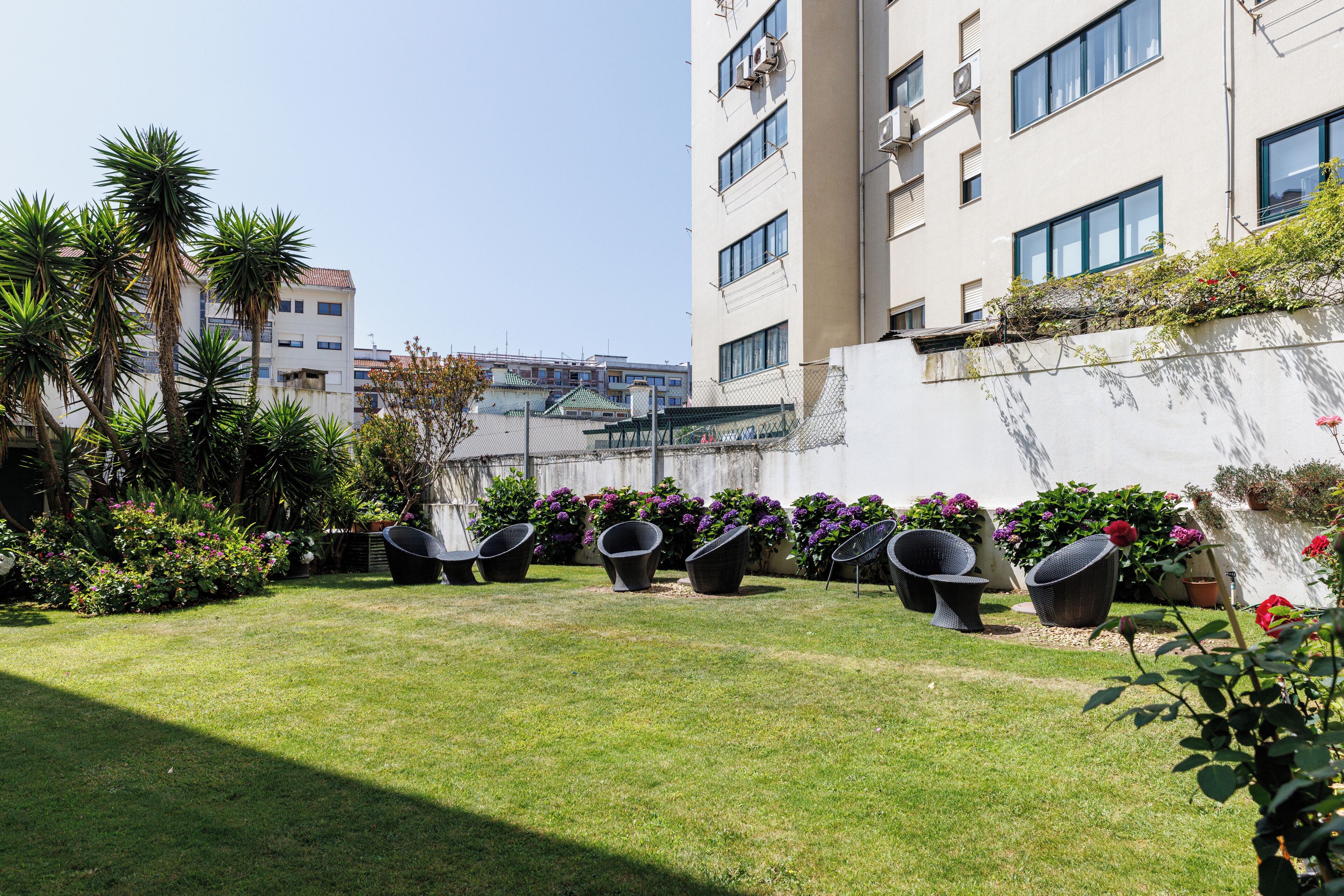 A courtyard with a lawn, outdoor seating, and potted plants.